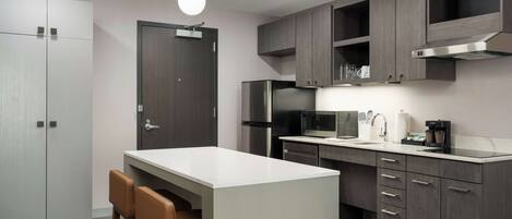 A modern kitchen with a central island, built-in appliances, and a bar seating area.