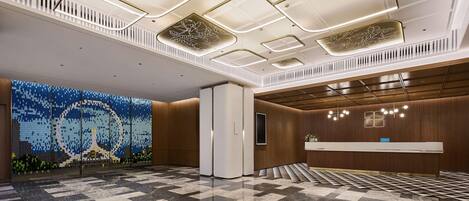 A spacious lobby with a checkered floor, a reception desk, and a decorative wall with a mosaic design.