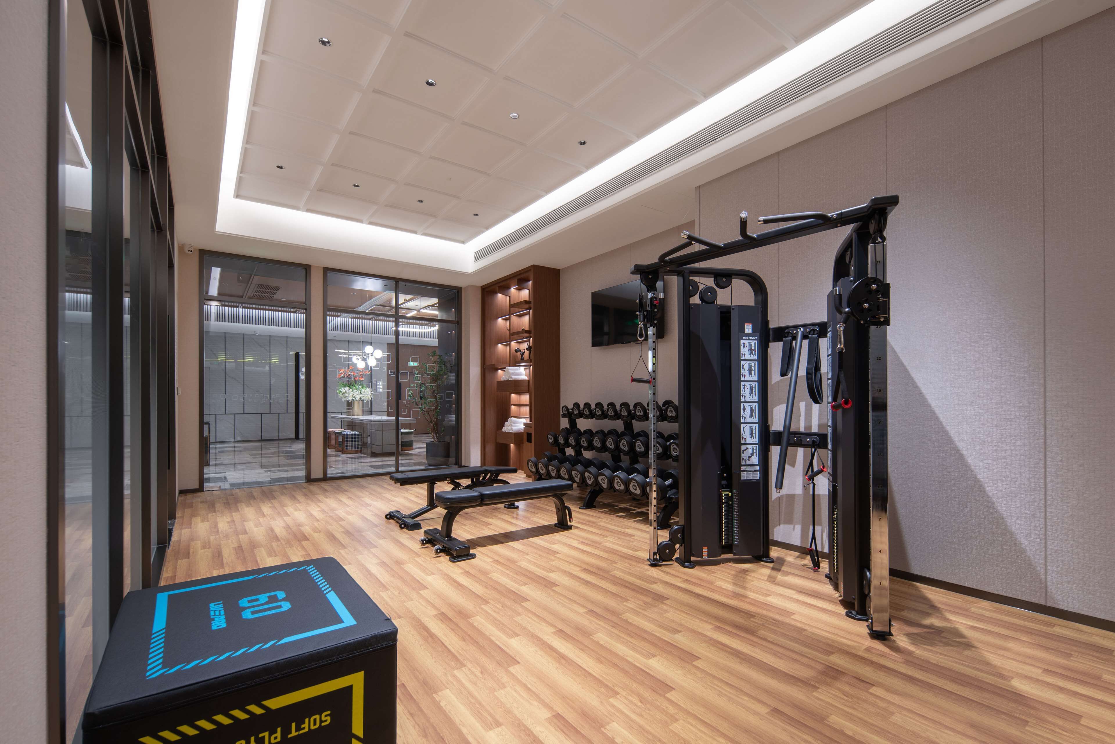 Un gimnasio con suelo de madera, equipo de ejercicio y una banca.