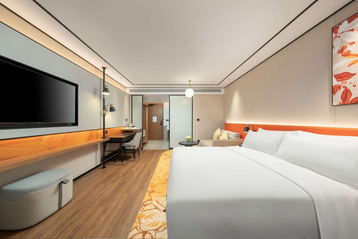 Ein modernes Hotelzimmer mit einem großen Bett, einem Schreibtisch, einem Flachbildfernseher und einer Sitzecke.
