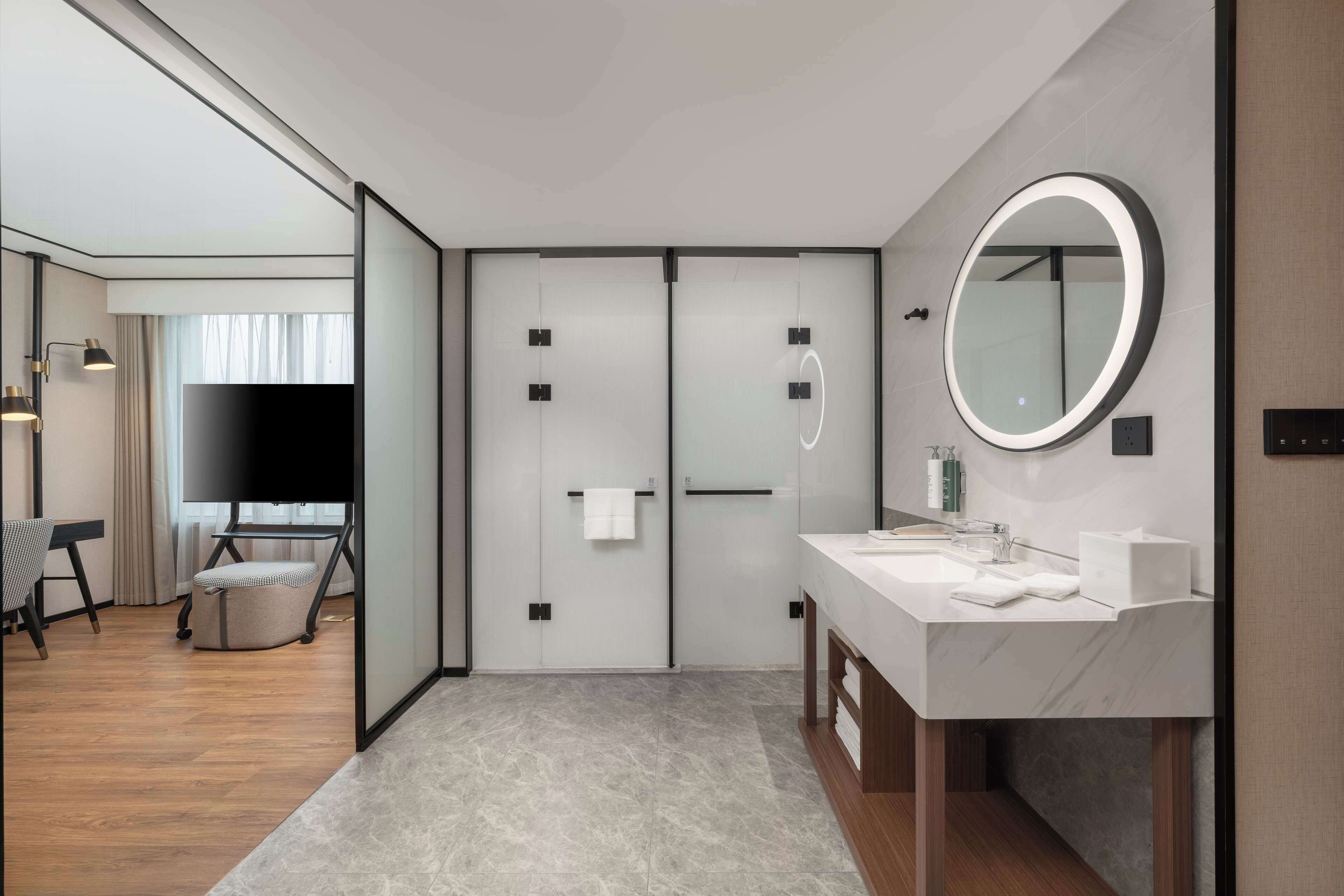 A modern hotel bathroom with a large mirror, a sink, and a vanity.