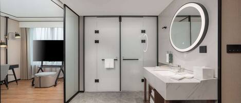 A modern hotel bathroom with a large mirror, a sink, and a vanity.