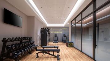 A modern gym with exercise equipment, a flat-screen TV, and a wooden floor.