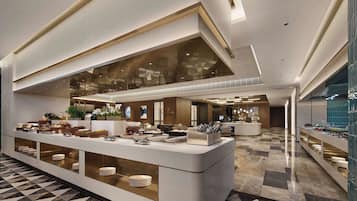 A modern hotel lobby with a central reception desk, a large glass window, and a check-in counter.