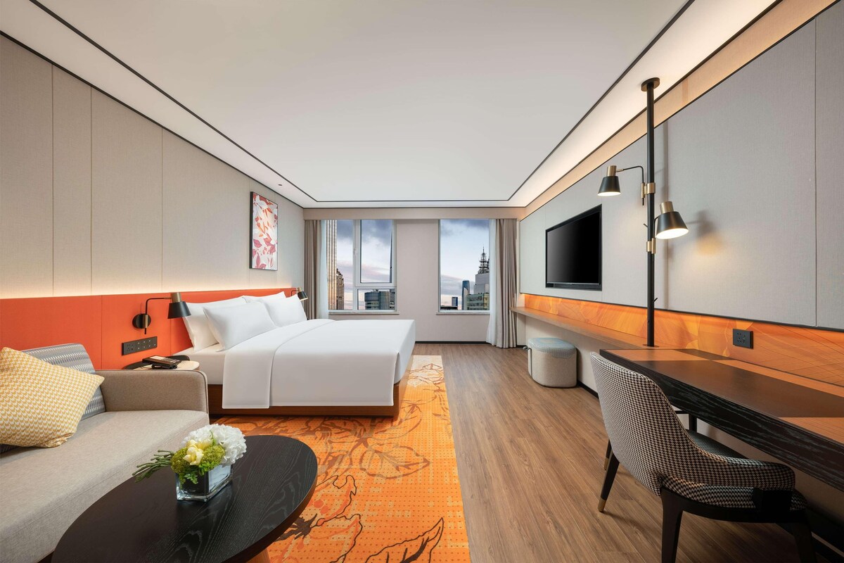 Une chambre d’hôtel moderne équipée d’un lit, d’un canapé, d’un bureau et d’une télévision.