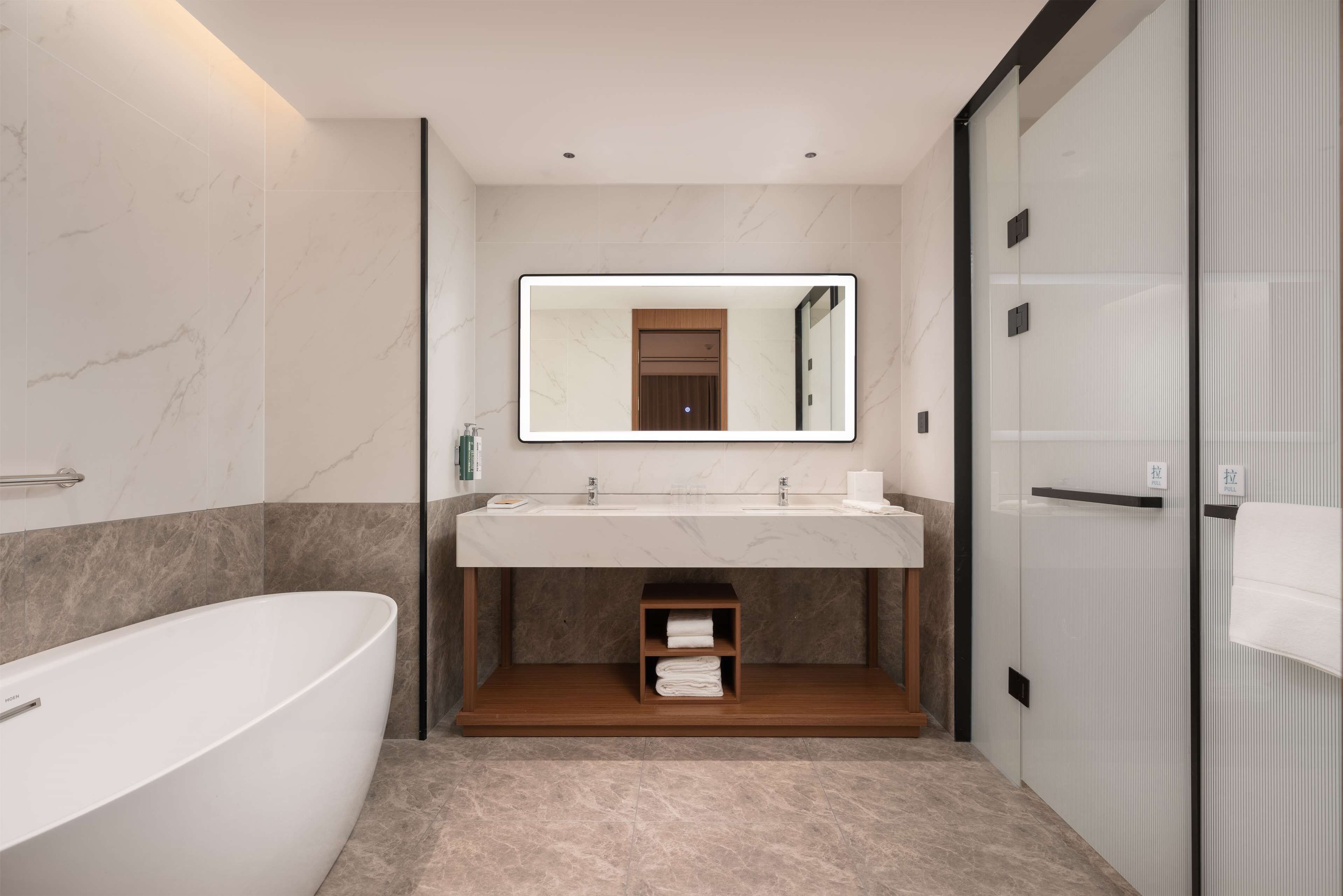 A modern bathroom with a freestanding bathtub, a large mirror above the sink, and a glass shower enclosure.