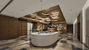 Un espace d’accueil moderne, doté d’un comptoir incurvé, d’un grand écran numérique et d’une plante décorative.