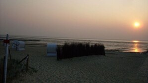 Een strand met een hek, een klein gebouw en een hekkenlijn.