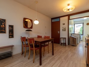 Ein Essbereich mit Holztisch und Stühlen, einem Spiegel, Wandbildern und einem Deckenventilator.