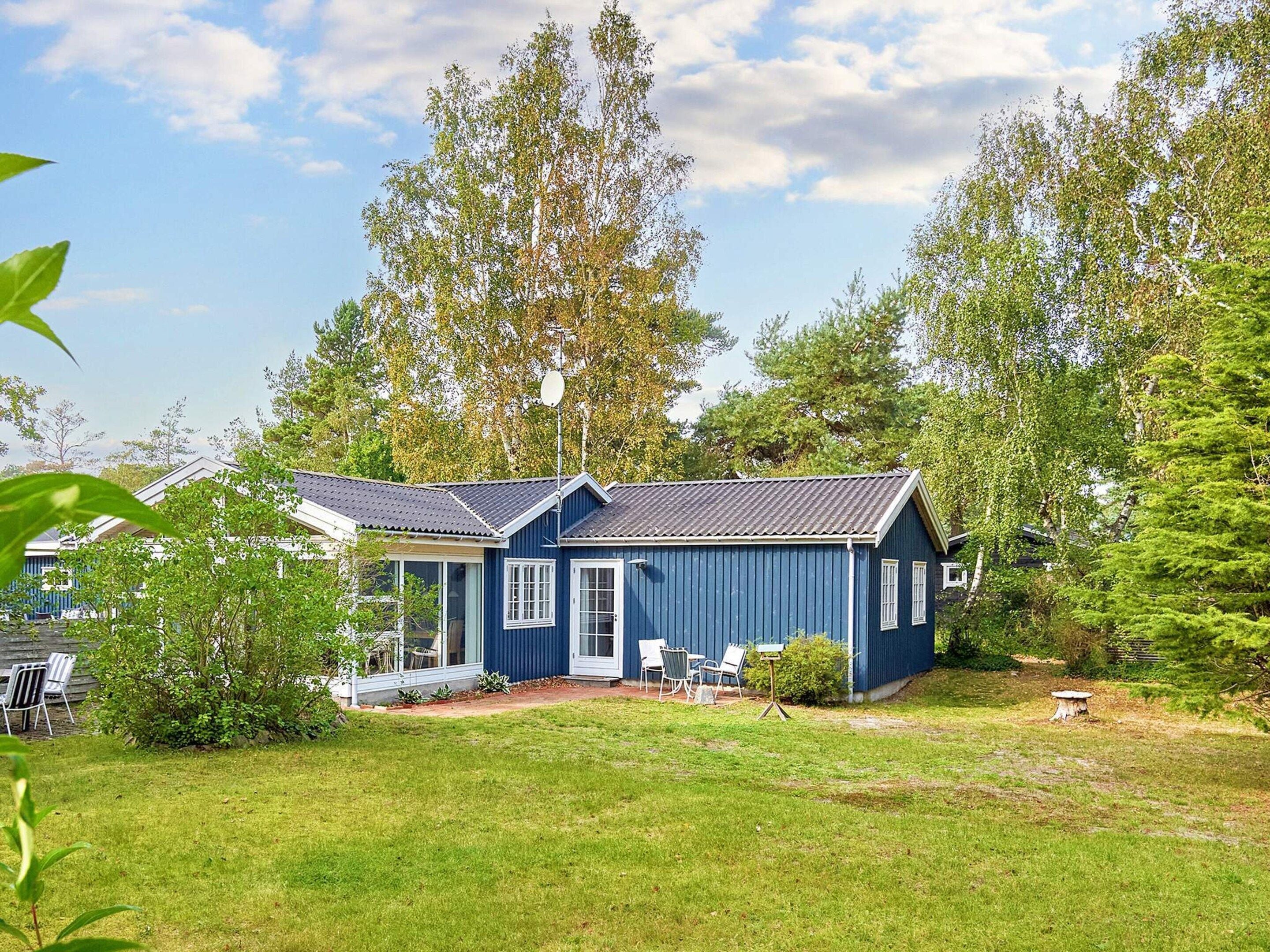 A blue house with a sloped roof, a front porch, and a small garden area.