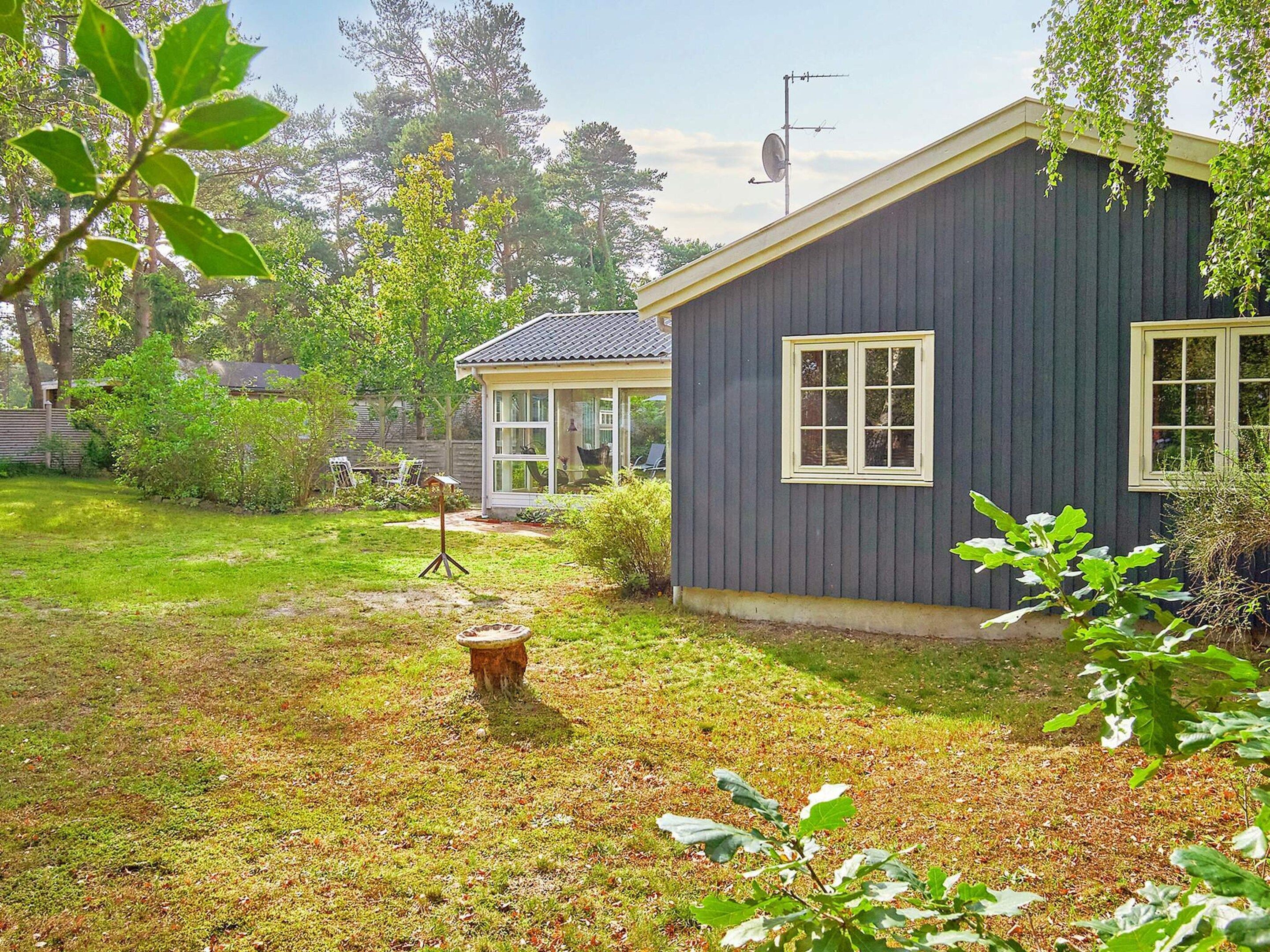 A house with a dark exterior, a small porch, and a well-maintained lawn.