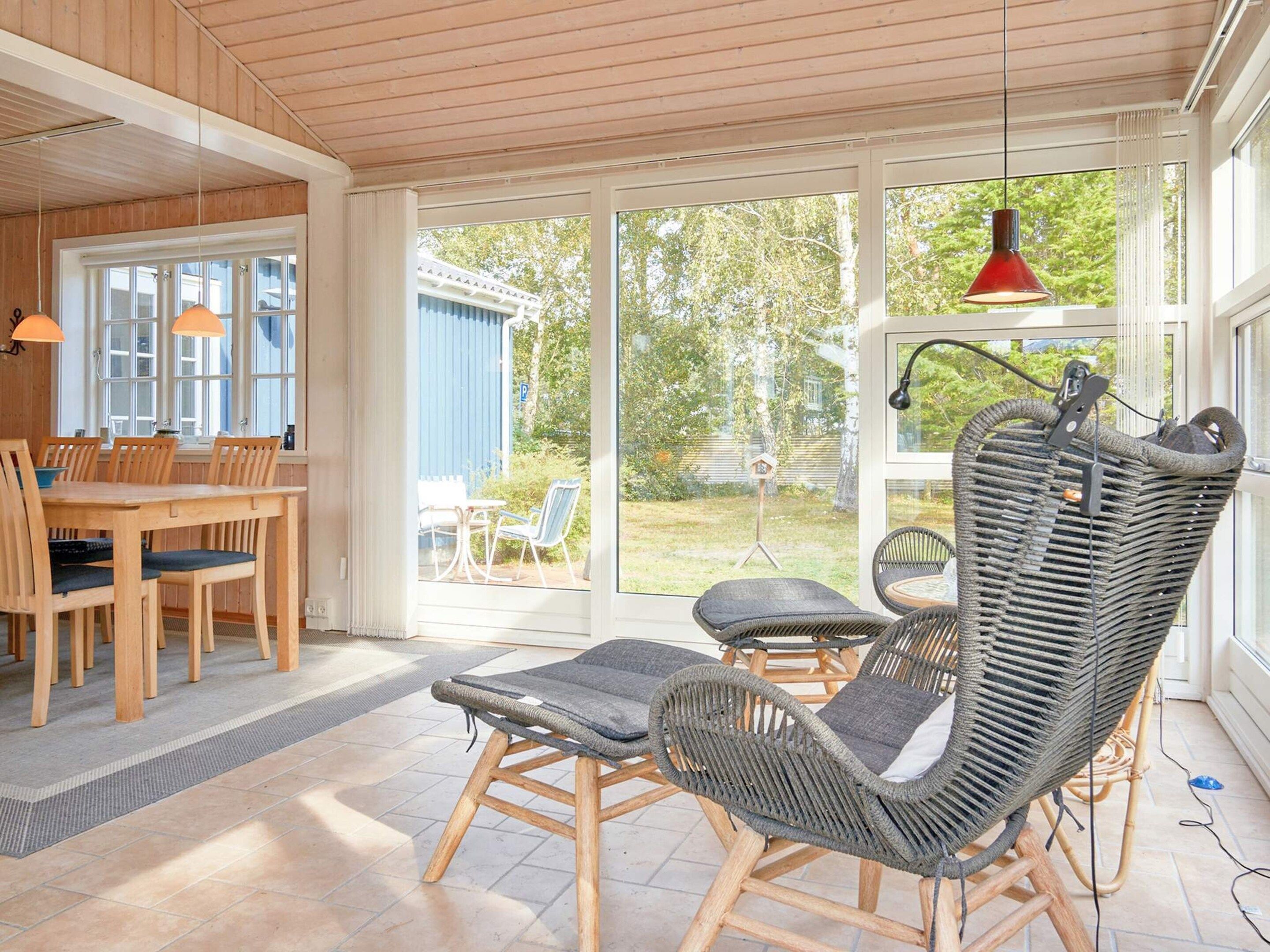 A sunlit room with a dining area, wicker chairs, and a view of the outdoors.