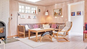 Una sala de estar acogedora con piso de madera, chimenea, un sofá, una mesa y una silla.