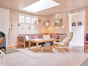 A cozy living room with a wooden floor, a fireplace, a sofa, a table, and a chair. - 4 Star Holiday Home in Nexo (Nexø)