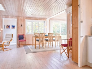 Une pièce chaleureuse avec un plancher en bois, une table à manger avec des chaises, un fauteuil à bascule et un fauteuil rouge.