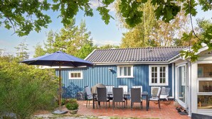 Una casa azul con un patio amueblado al aire libre y un paraguas grande.