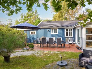 A blue house with a patio area featuring outdoor furniture and a large umbrella. - 4 Star Holiday Home in Nexo (Nexø)