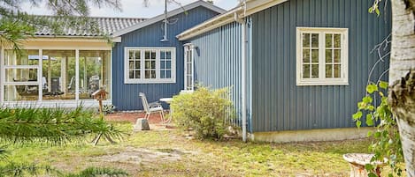 A house with a blue exterior, a visible satellite dish, and a small garden area with a bird feeder.