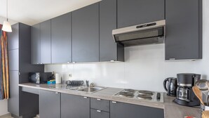 A modern kitchen with grey cabinets, a stainless steel sink, a built-in stove, and a coffee maker. - Studio on the 5th Floor With a Beautiful View (Middelkerke)