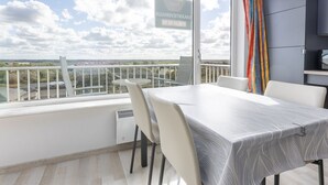 A balcony with a table and chairs, a view of the countryside, and a sign indicating a restaurant. - Studio on the 5th Floor With a Beautiful View (Middelkerke)
