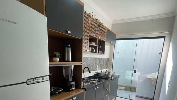 A modern kitchen with a refrigerator, stove, and cabinets. - Casinha33, O Aconchego da Tríplice Fronteira! (Jardim Cataratas Foz do Iguaçu)