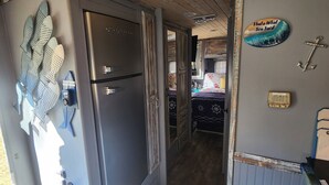 A compact RV interior with a kitchenette, a refrigerator, a fire extinguisher, and a small table. - The Holy Mackerel 
Family and pet friendly  (Perry)
