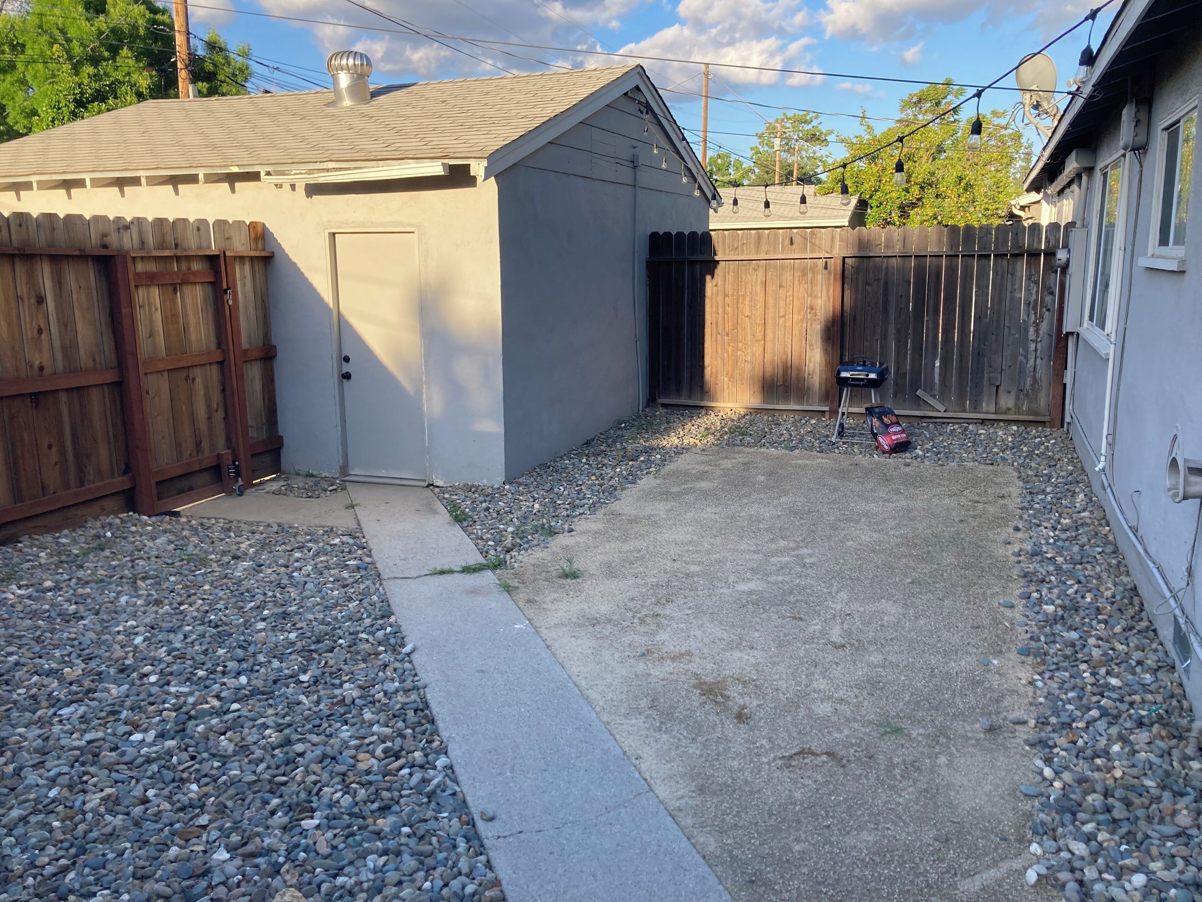 A backyard with a shed, a wooden fence, and a gravel area.