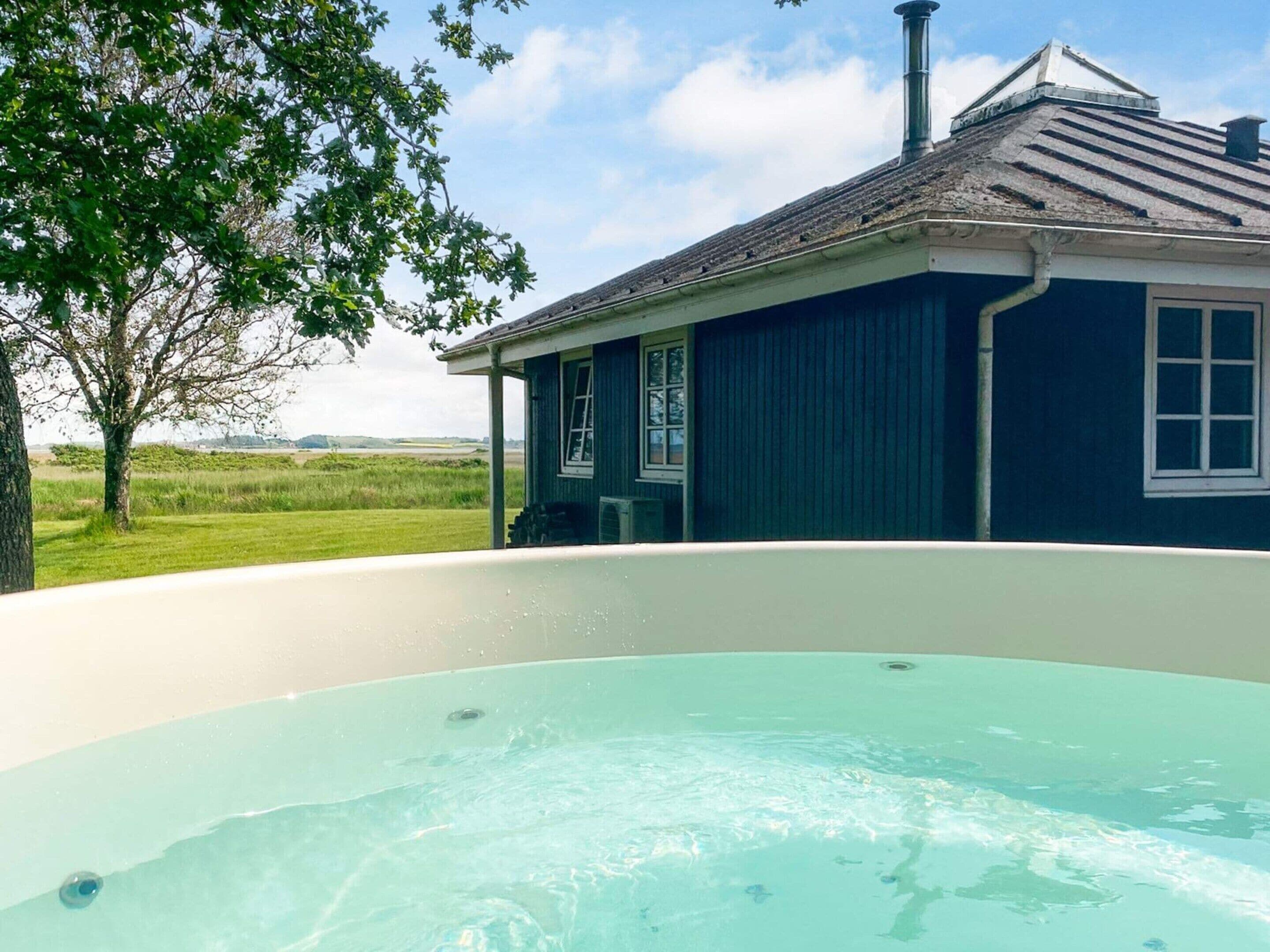 A hot tub with a view of a house and a tree.