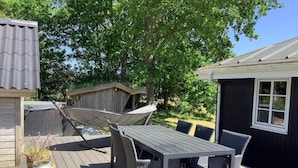 An outdoor deck with a table and chairs, a hammock, and a wooden structure.