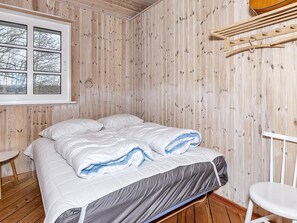 A room with a bed, a window, and a wooden wall.