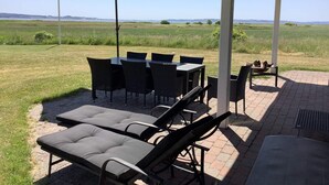 An outdoor patio with a table and chairs, a lounge chair, and an umbrella.