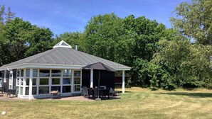 A covered patio with outdoor seating and a view of a grassy area.