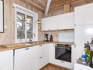 A kitchen with white cabinets, a wooden countertop, a sink, a coffee maker, and an oven. - 4 Star Holiday Home in Thisted (Thisted)