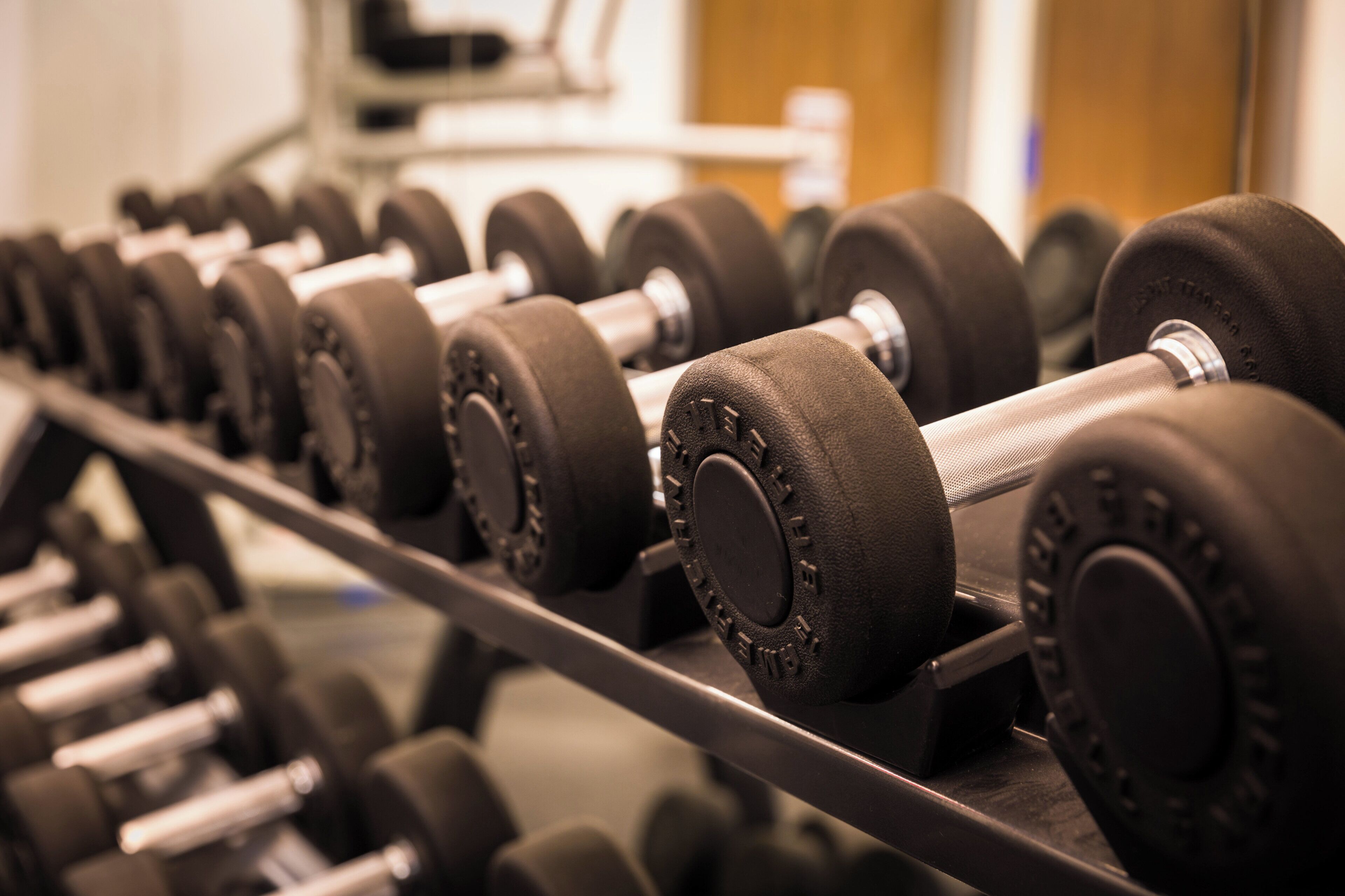 A rack of black dumbbells with adjustable weights.