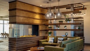 Una sala moderna con chimenea, sofá de cuero verde, mesa de centro de madera e iluminación colgante.