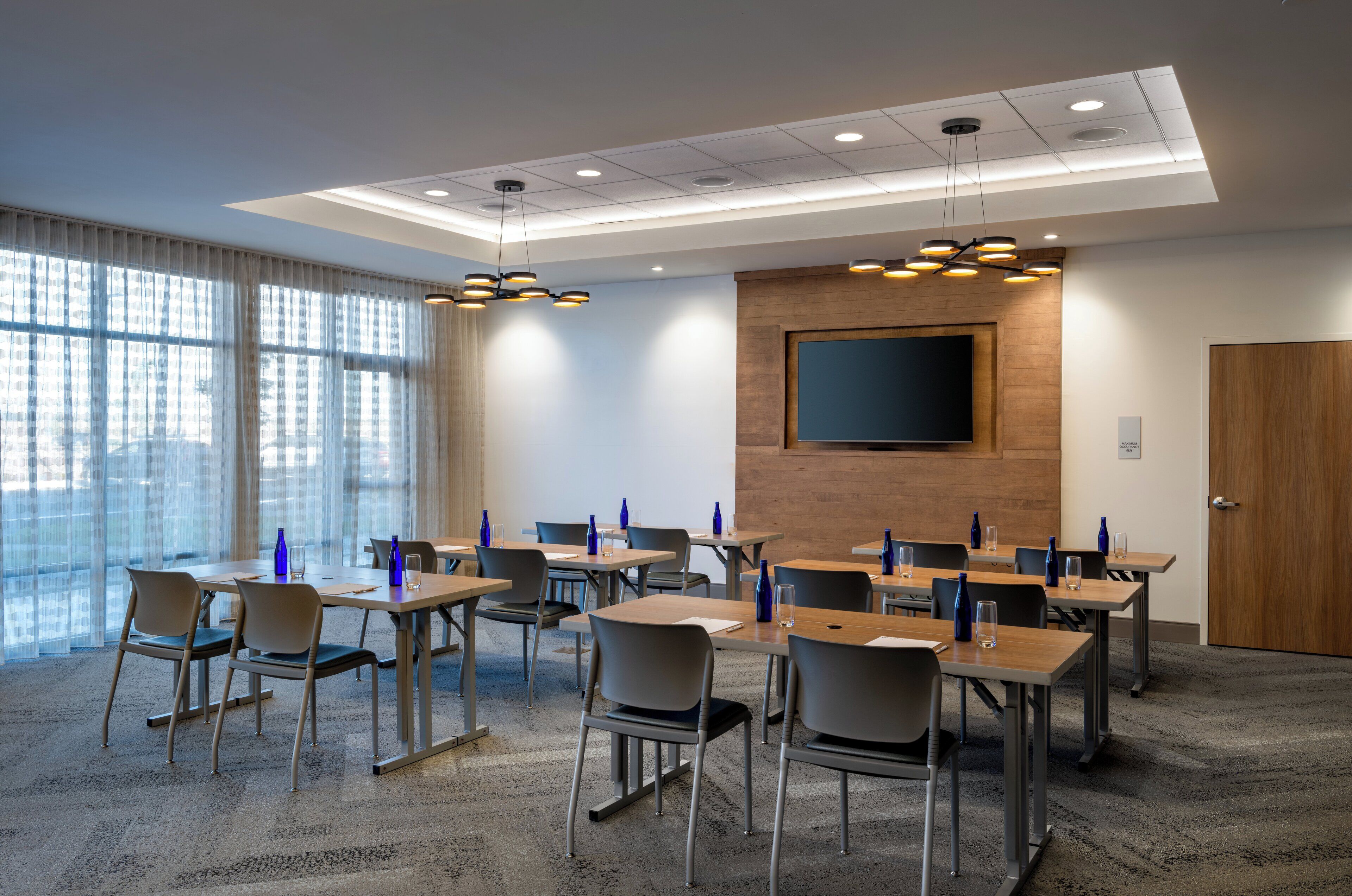 A conference room with tables, chairs, and a large screen.