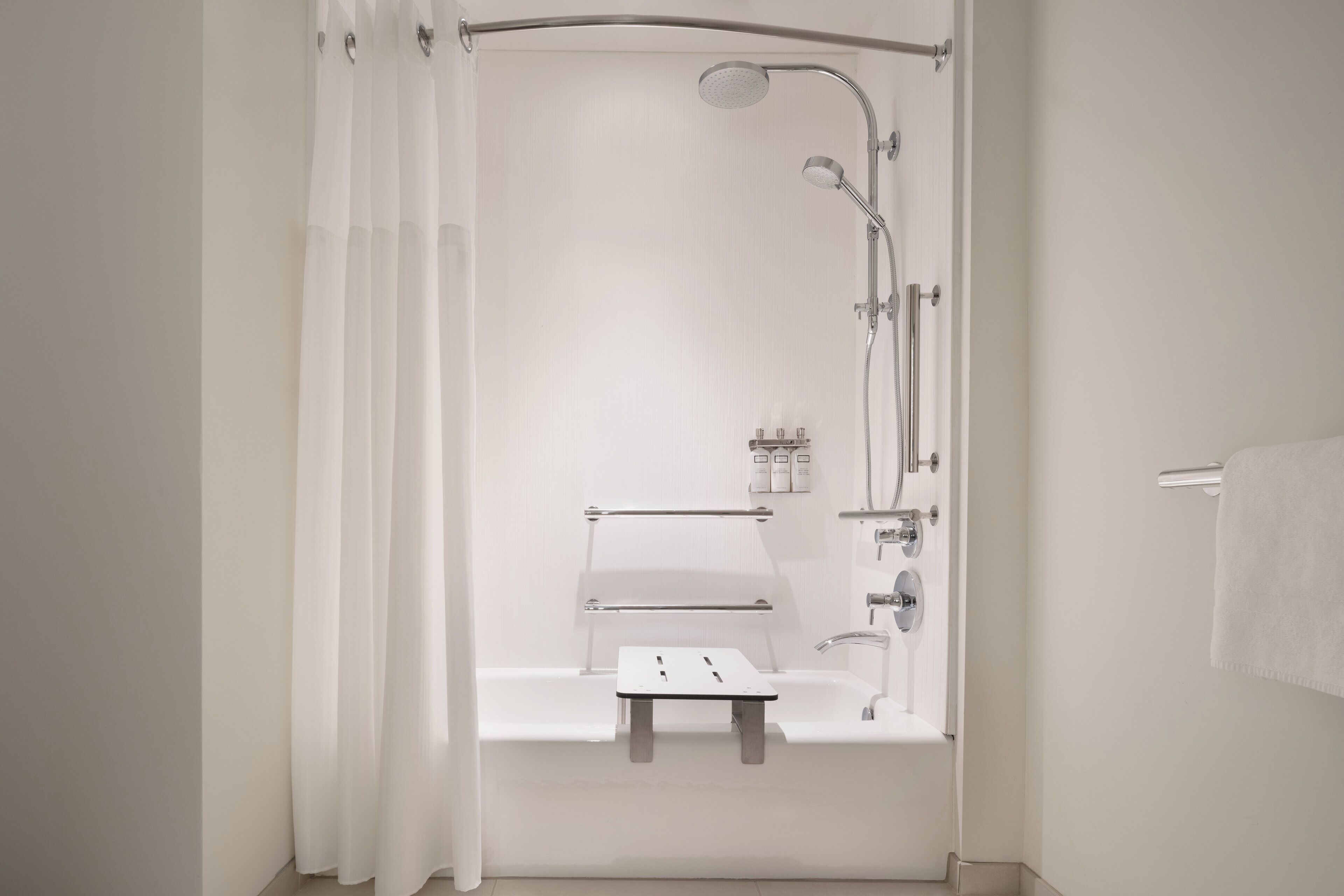 A modern bathroom with a walk-in shower, a bathtub with a small shelf, and a toilet.