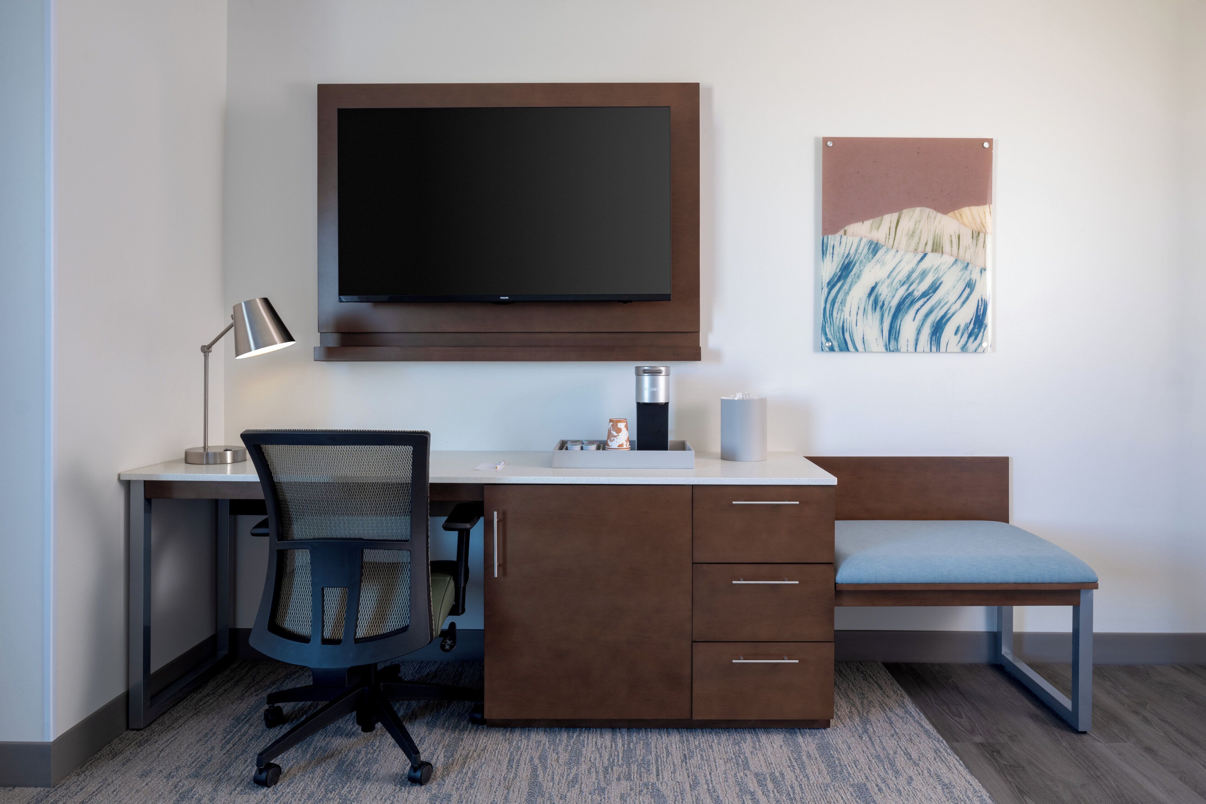 Een moderne kantoorruimte met een bureau, stoel en een wandgemonteerde flatscreen-tv.