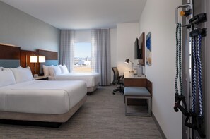 A hotel room with two beds, a desk with a chair, a treadmill, and a view of the outdoors. - EVEN Hotel Bozeman Yellowstone Intl Arpt​ by IHG (Belgrade)