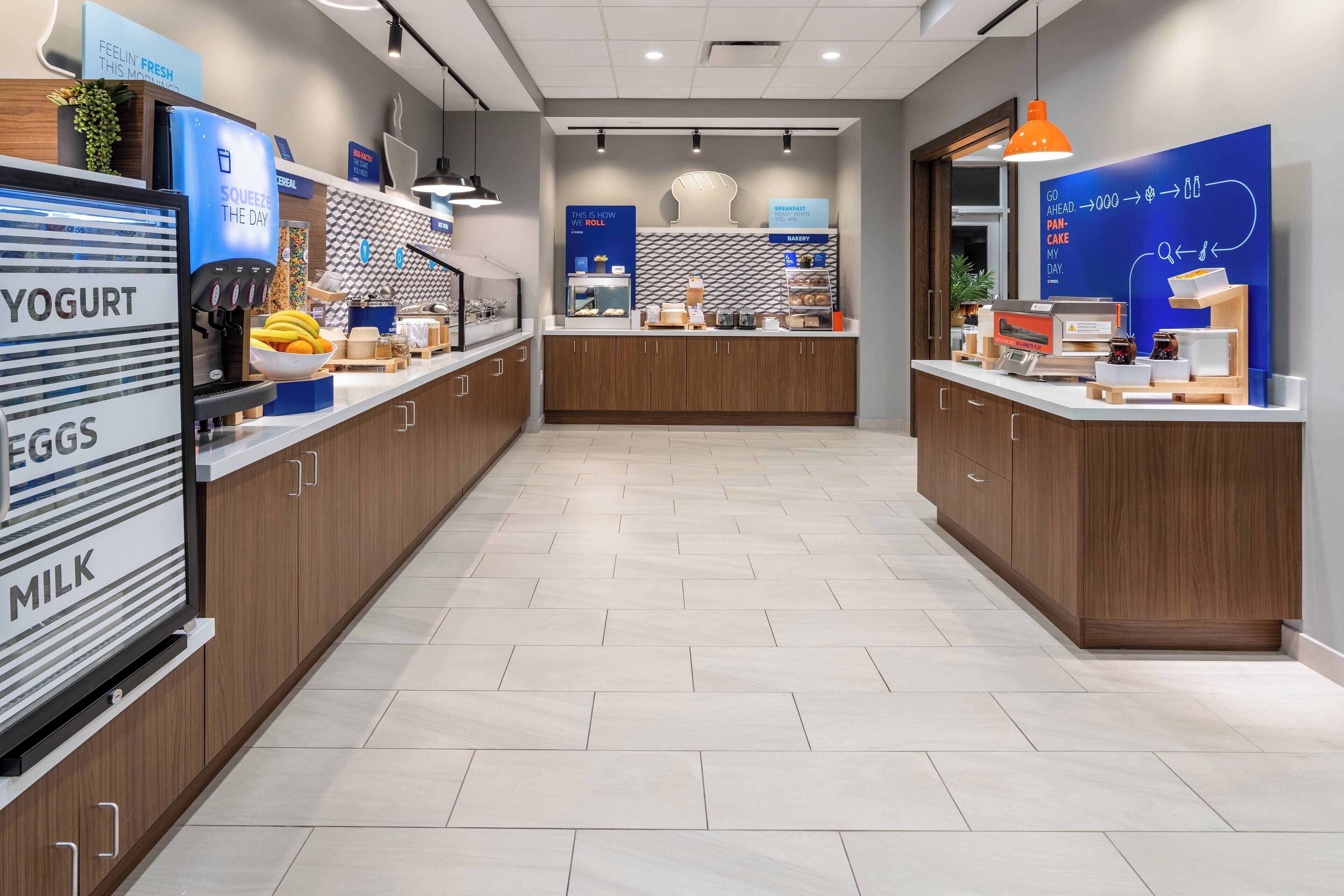A modern breakfast area with a counter displaying various food items and a blue sign with text.
