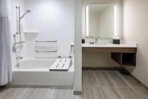 Une salle de bain moderne équipée d’une baignoire, d’une douche et d’un meuble-lavabo avec un miroir.
