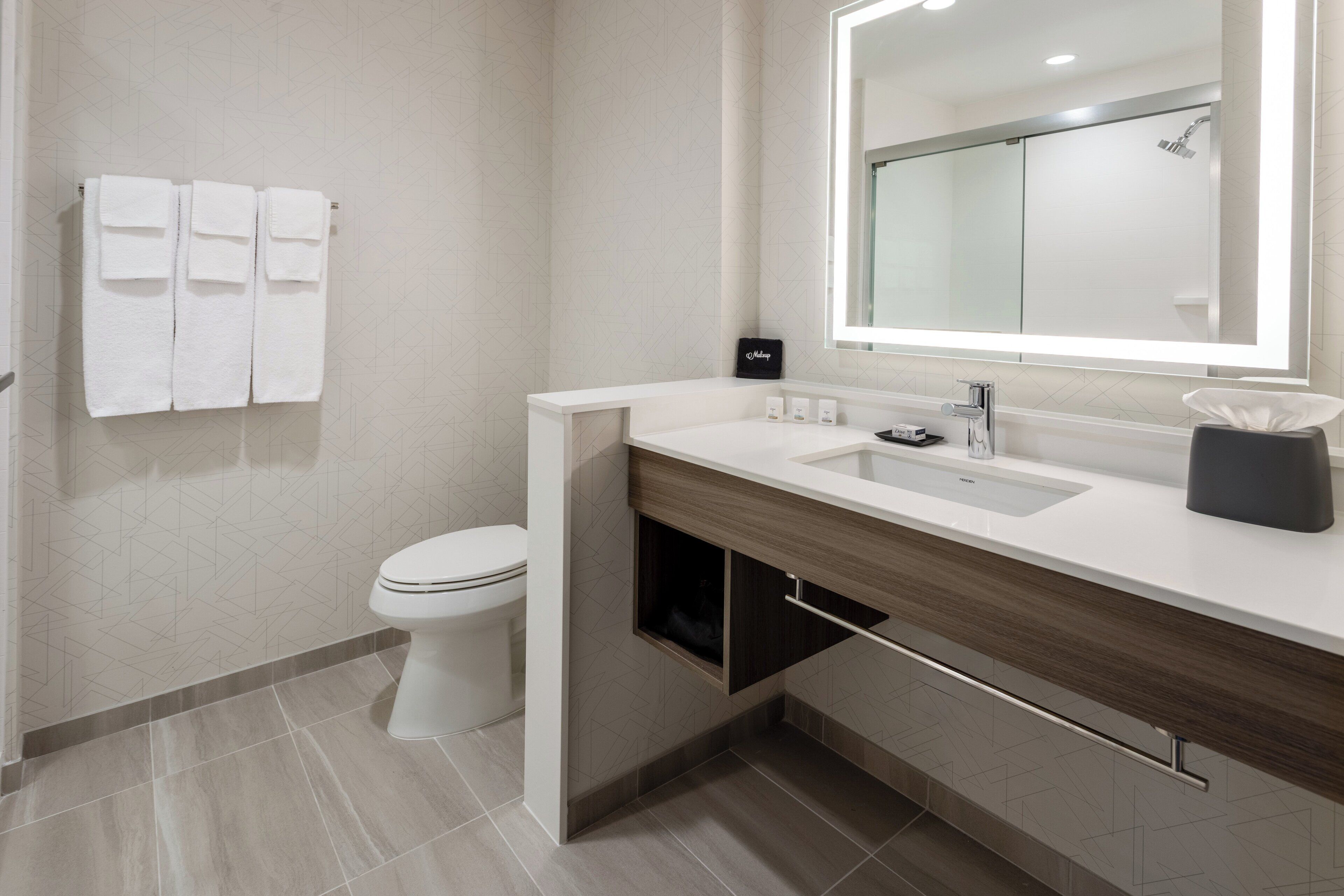 A modern bathroom with a toilet, a sink, and a mirror.
