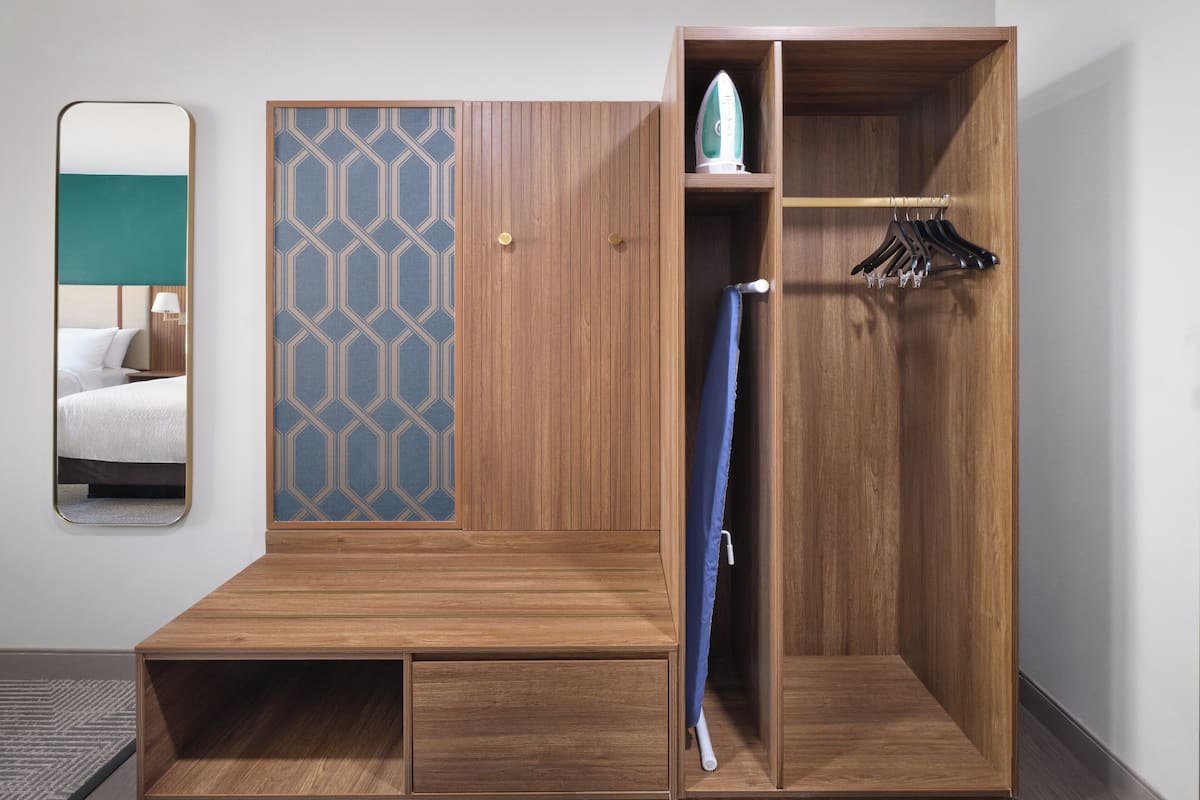 Un armario de madera con espejo, barra para colgar ropa y cortina de ducha azul.