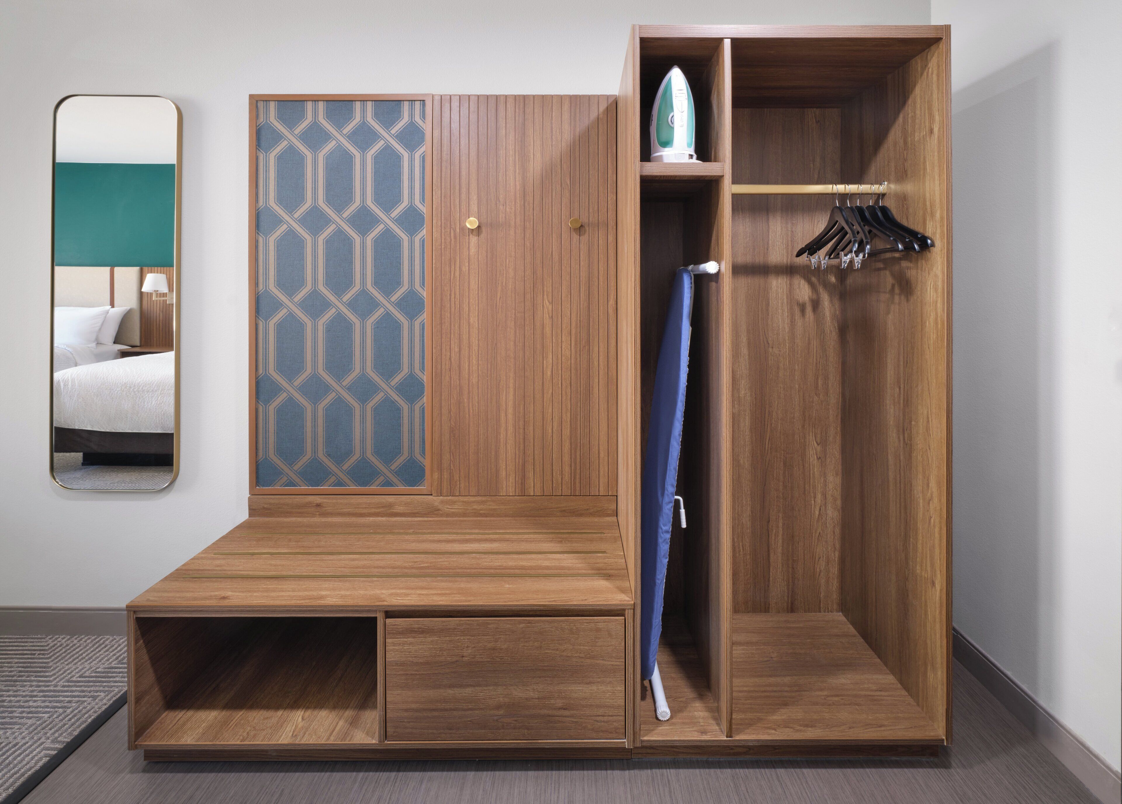 A wooden wardrobe with a mirror, a hanging rack, and a blue shower curtain.
