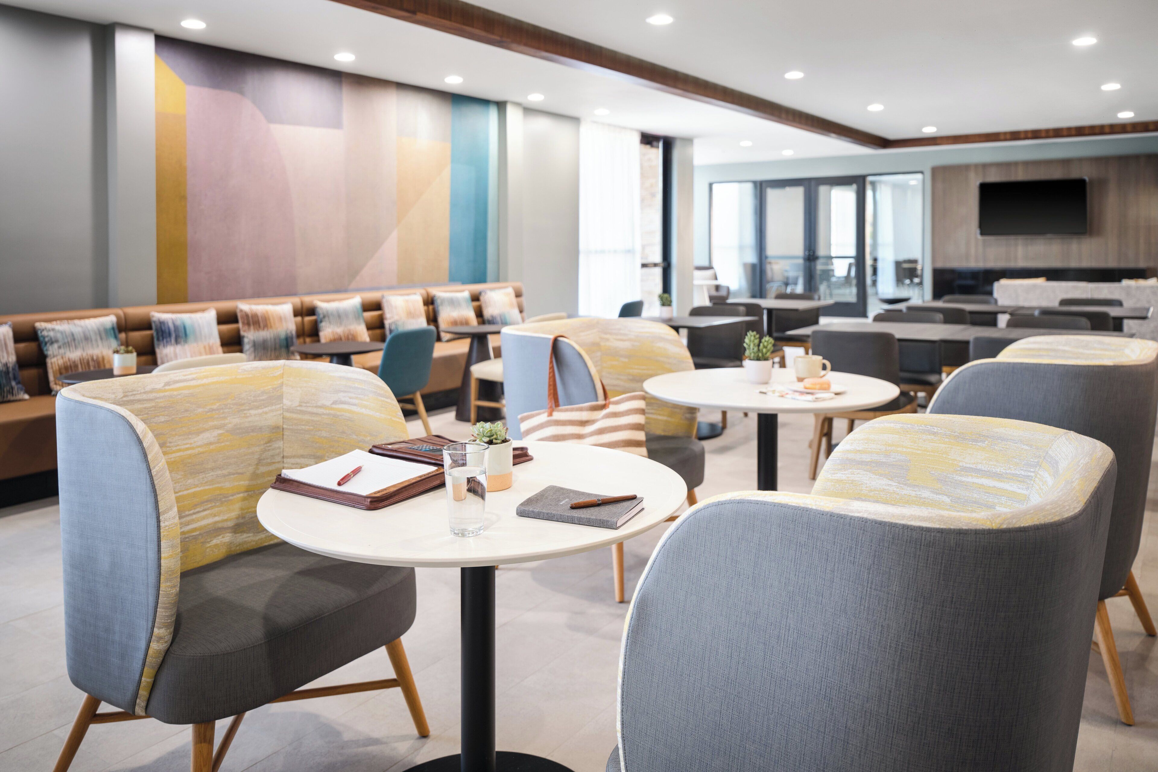 Un espace détente moderne, doté de sièges confortables, de tables et d’un grand écran de télévision.