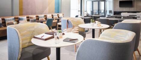 Un espace détente moderne, doté de sièges confortables, de tables et d’un grand écran de télévision.