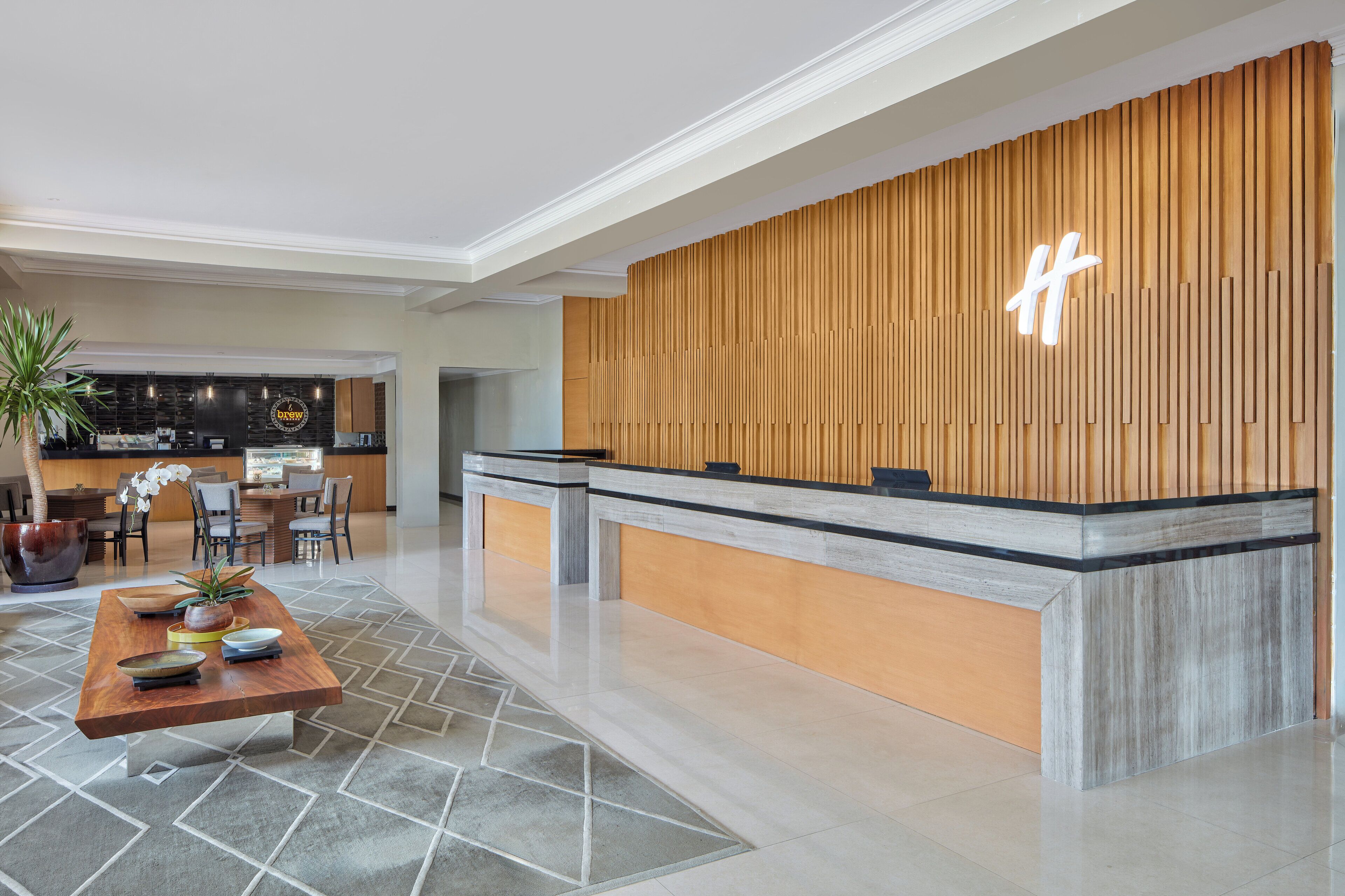 A reception area with a wooden reception desk, a seating area with a table and chairs, and a bar in the background.