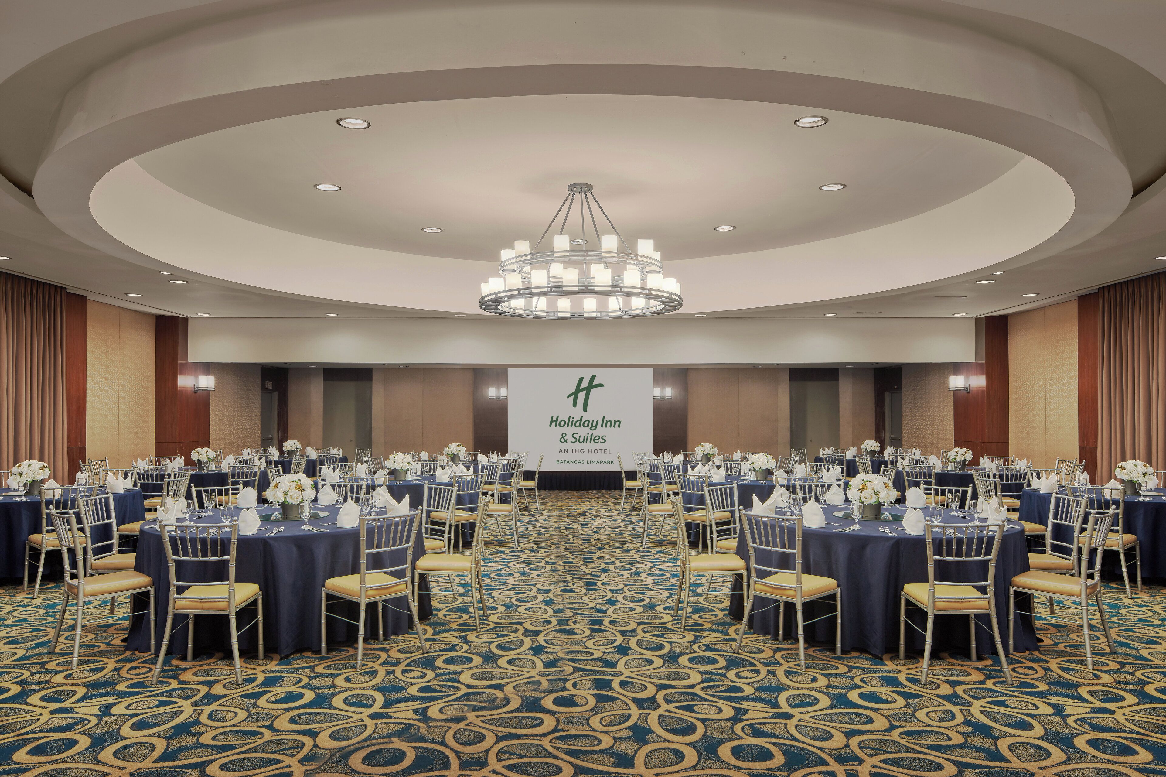 A conference room with round tables, chairs, and a chandelier.