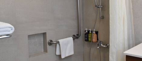 A modern bathroom with a shower, grab bars, a towel rack, and a shower curtain.