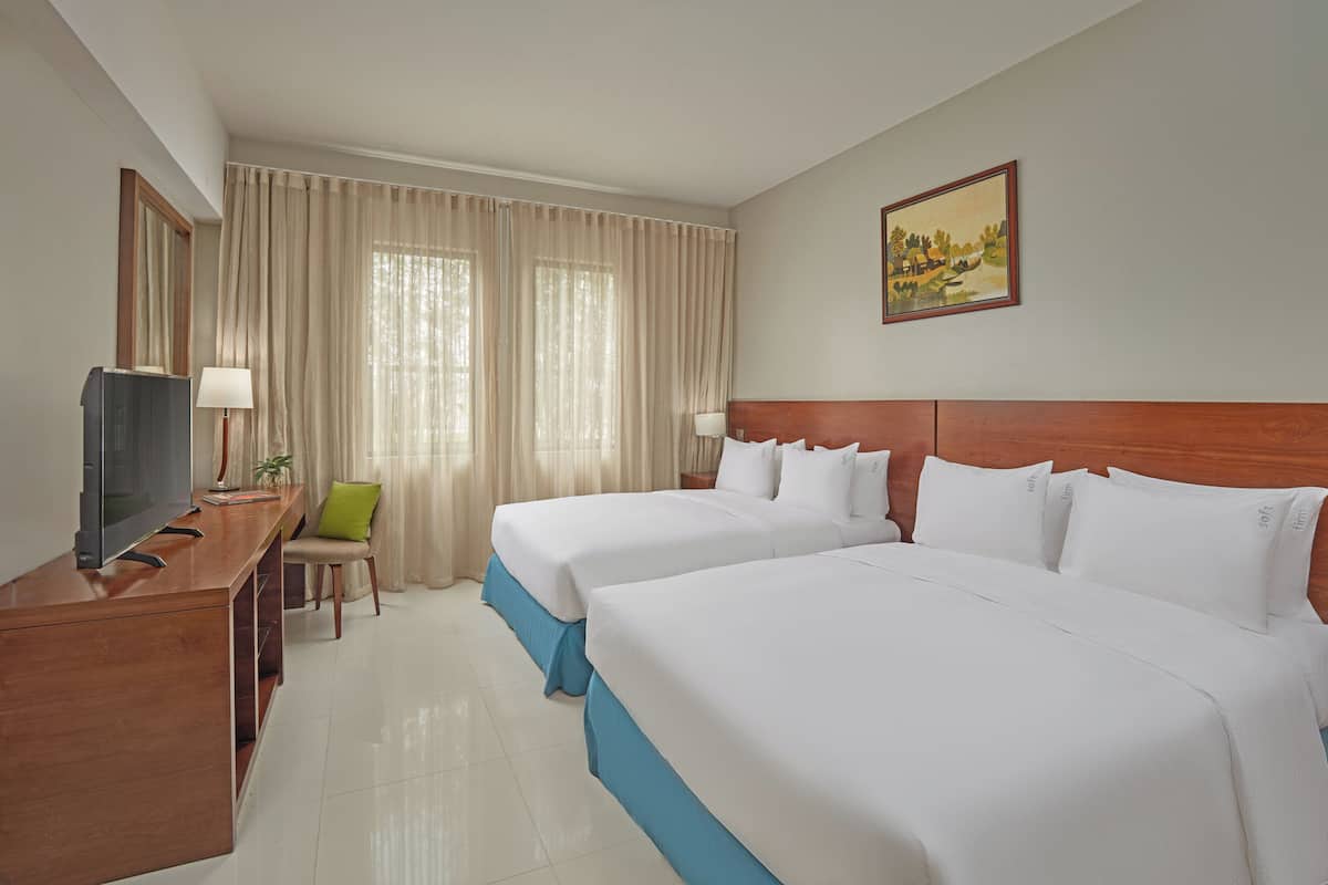 A hotel room with two beds, a desk with a television, a chair, and a painting on the wall.